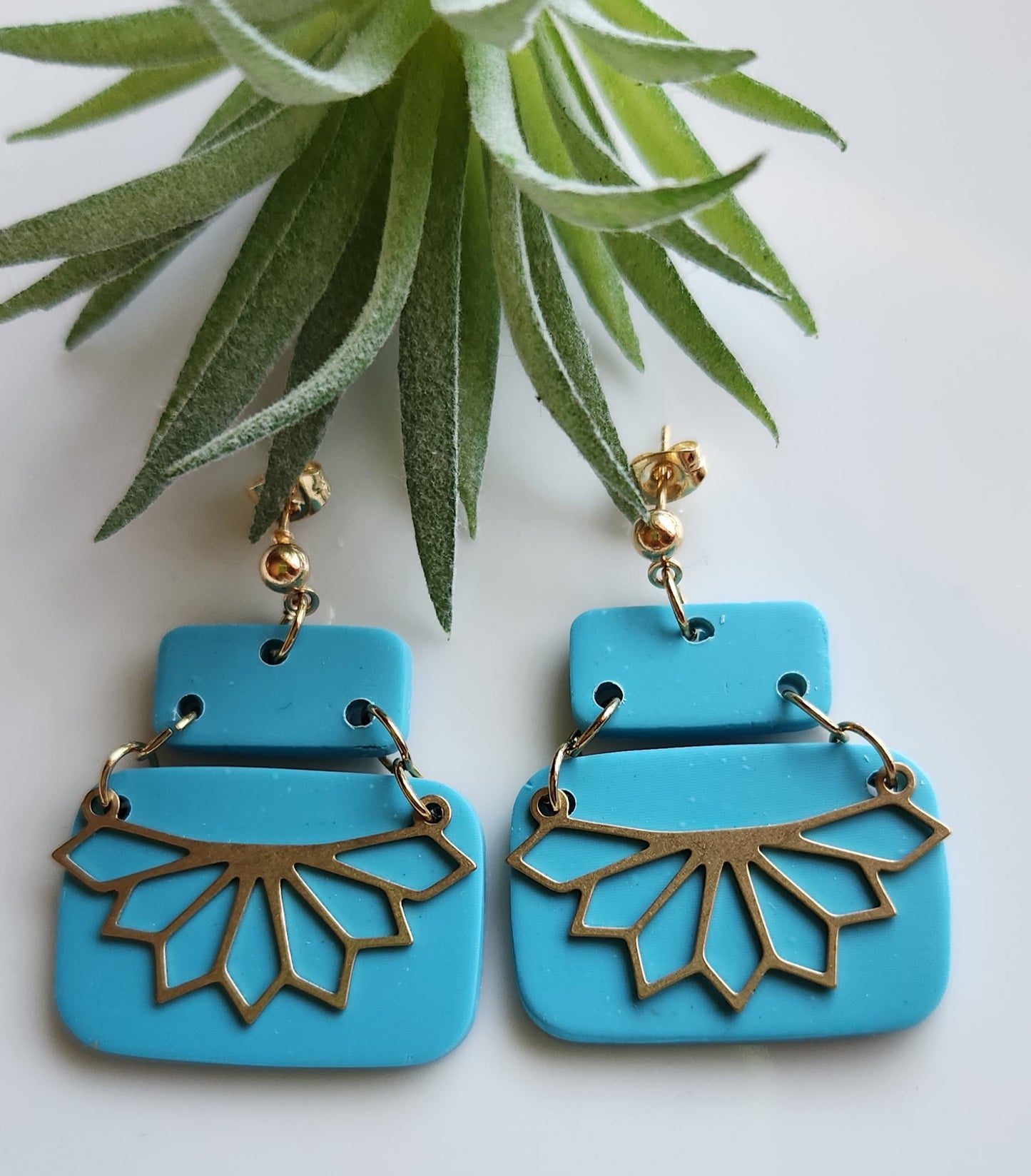 Handmade polymer clay earrings! Stunning turquoise clay color earrings! Two polymer clay rectangles create this earring with gold plated circle stud and jump rings. Bottom rectangle includes a brass shape pointed teardrop cutout half cirle pendant. Matte look, lightweight and approximately 1.5". Please note earrings are made from a handmade polymer clay combination into a slab. Therefore, each earring pair might differ slightly from photo displayed making each pair unique!