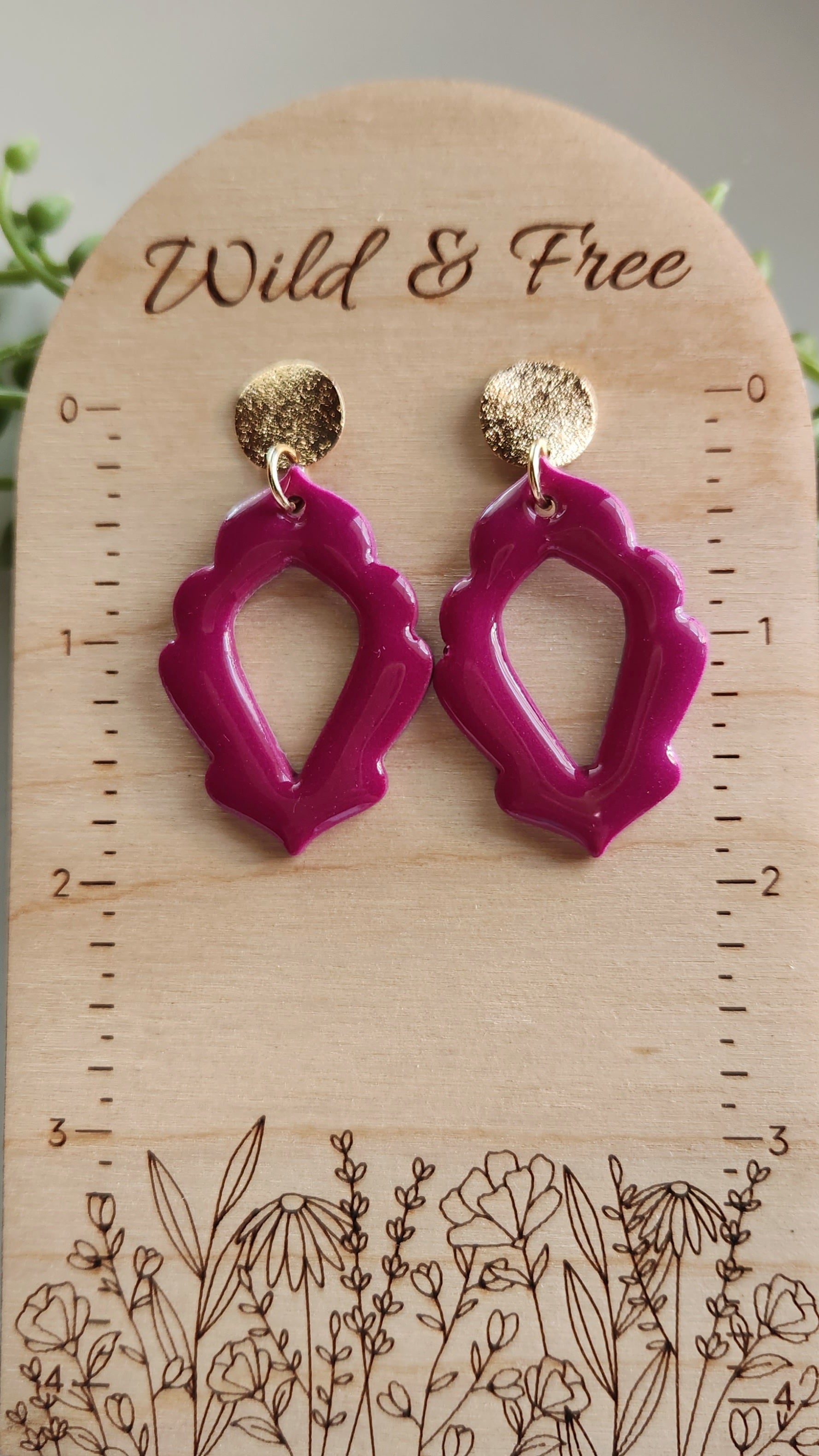 Handmade polymer clay earrings! Stunning fuchsia color clay mix creates this dangle. Design is an open oval shape with a floral border cutout and a shimmery gold plated circle stud completes this look. Lightweight and with resin for glossy finish. Approximately 2" long.