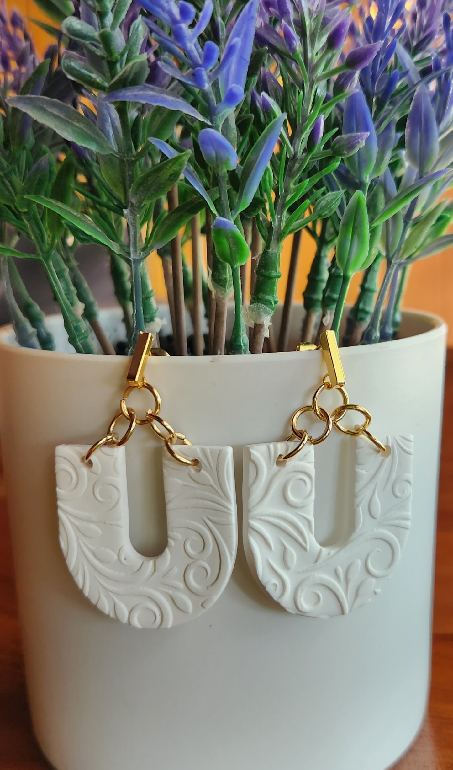 Handmade polymer clay earrings! Beautiful, bold, lightweight clay earrings! These earrings are designed in a u shape with white clay as a base and textured as vines throughout. A gold plated skinny rectangle is used as a stud to complete this beautiful piece. Matte look and approximately 2" long.