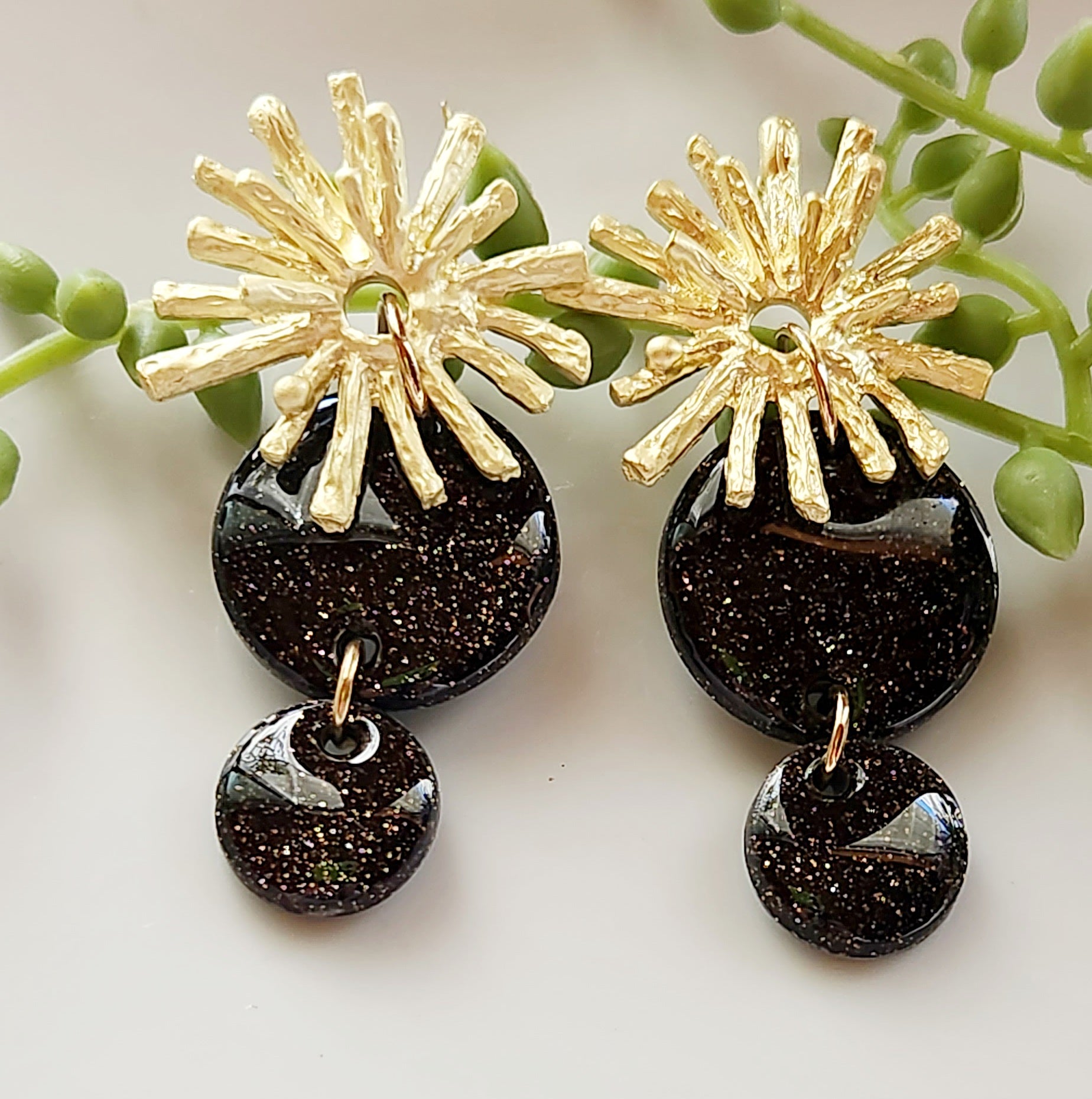 Handmade polymer clay earrings! Lightweight show-stopper earring design! The stunning earring design includes an alloy gold plated floral stud and two black shimmery polymer clay circles. Perfect for any occasion! Meant to stand out! Lightweight, with resin for a glossy look, and approximately 2" long.