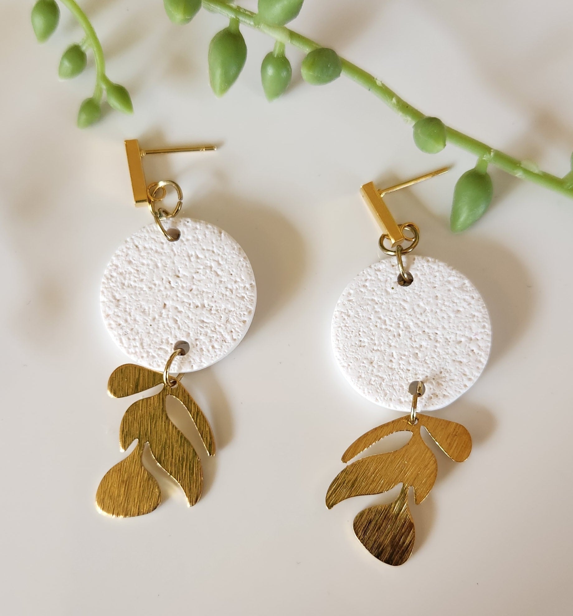 Handmade polymer clay earrings! This beutiful design is made out of white textued clay with a circle shape. There is a beautiful brass gold vine dangle giving it a unique design. A gold plated thin rectangle stud completes this look. Lightweight, matte and approximately 2" long.