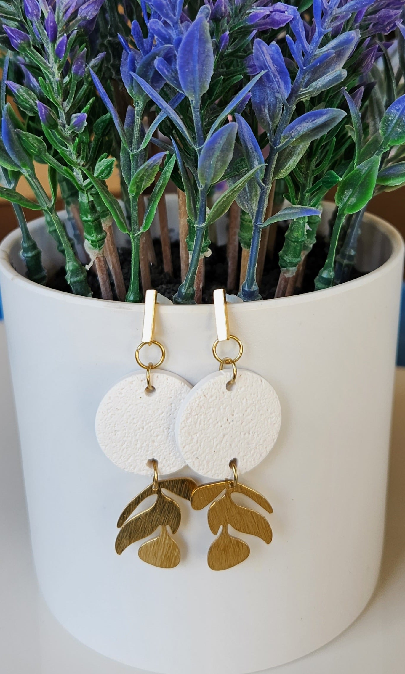 Handmade polymer clay earrings! This beutiful design is made out of white textued clay with a circle shape. There is a beautiful brass gold vine dangle giving it a unique design. A gold plated thin rectangle stud completes this look. Lightweight, matte and approximately 2" long.