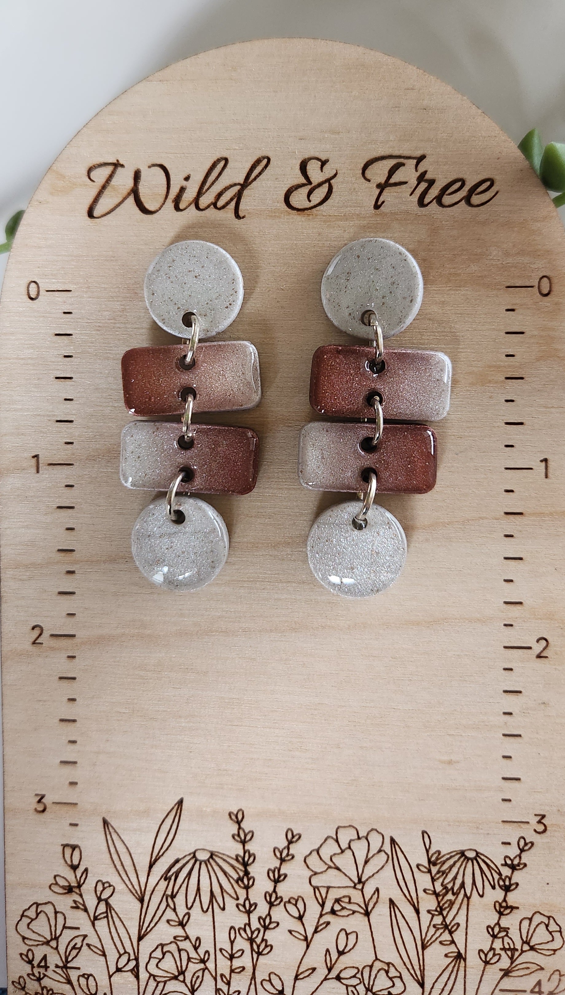 Handmade polymer clay earrings! These earrings are a unique color combination of speckled pearl white and bronze. The design for these earrings consist of two speckled pearl white circles on top and bottom of dangle. Ther are two small rectangles in the middle with pearl white and bronze blend. This bronze blend reminds me of the mountain color of Zion! Lightweight and with resin for a glossy look. Approximately 1.5" long.