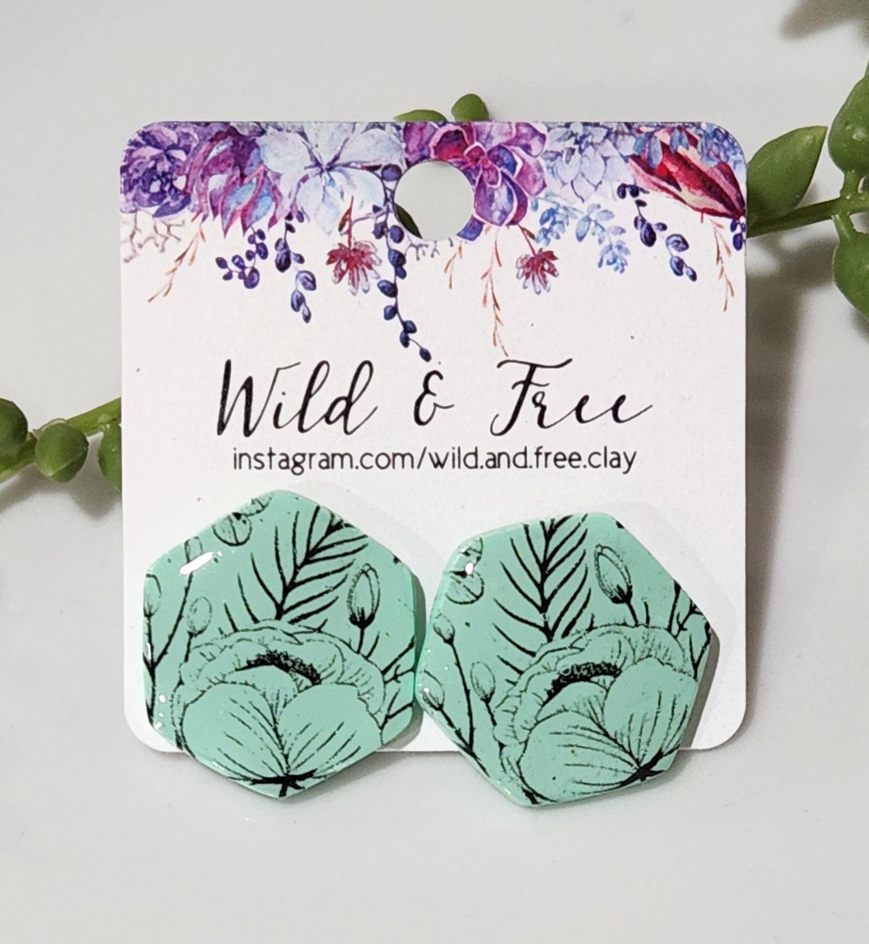 Handmade polymer clay earrings! Hexagon shape stud with mint background clay and black floral design paint. These stud earrings are perfect for any outfit and a staple accessory item for all. Studs are approximately 1" long and with resin for a glossy look.