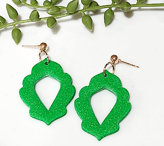 Handmade polymer clay earrings! This bold green color clay blend creates a stunning earring sure to make a statement. This dangle has a gold plated small circle stud followed by a clay piece of oval shape with floral outline and an open middle. They are lightweight and approximately 2" long.