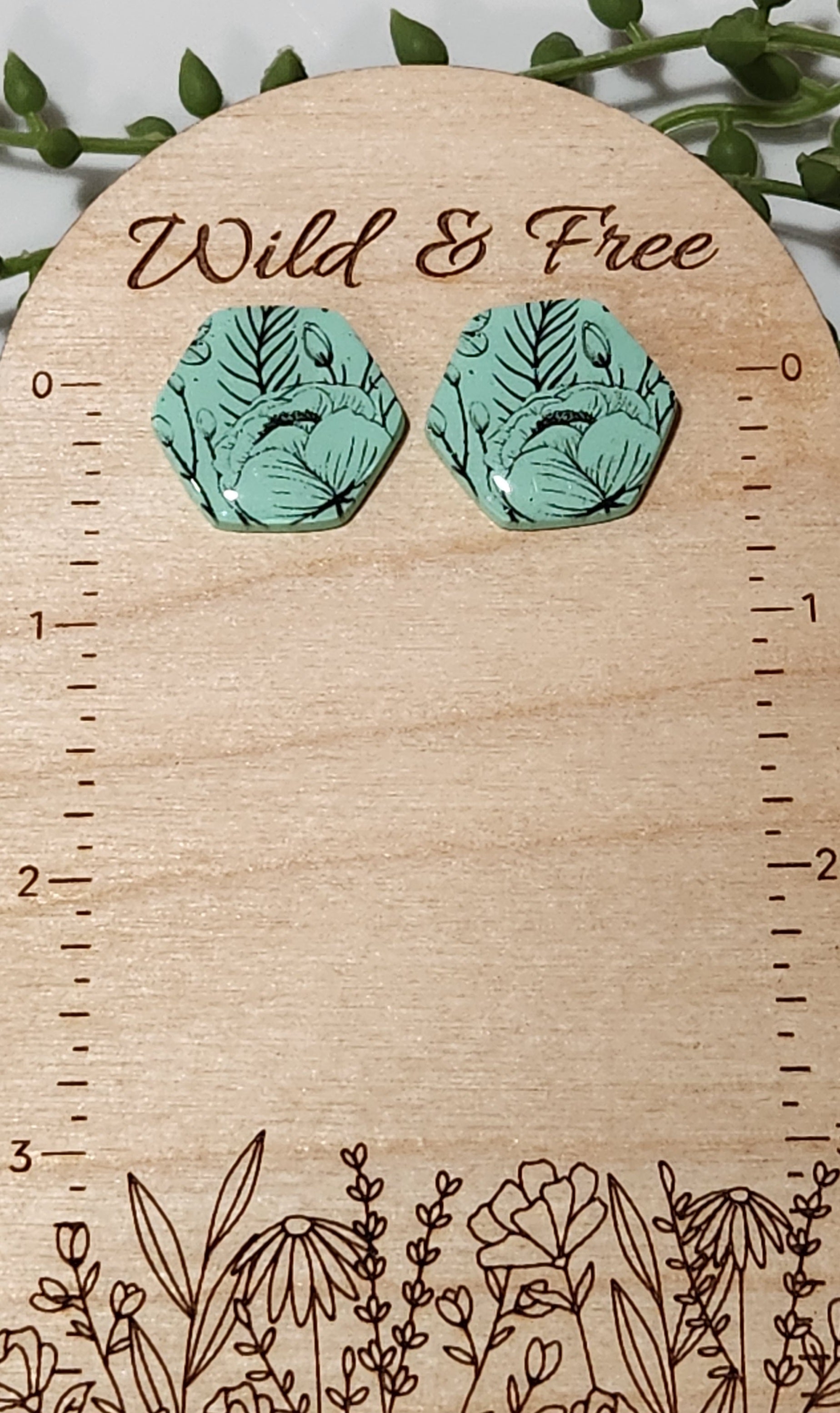 Handmade polymer clay earrings! Hexagon shape stud with mint background clay and black floral design paint. These stud earrings are perfect for any outfit and a staple accessory item for all. Studs are approximately 1" long and with resin for a glossy look.