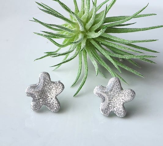 Handmade polymer clay earrings! These silver shimmery clay blend earring studs are the perfect sparkle for any outfit! The rounded star shaped studs are lightweight and with resin for a glossy look. Approximately .5" long.