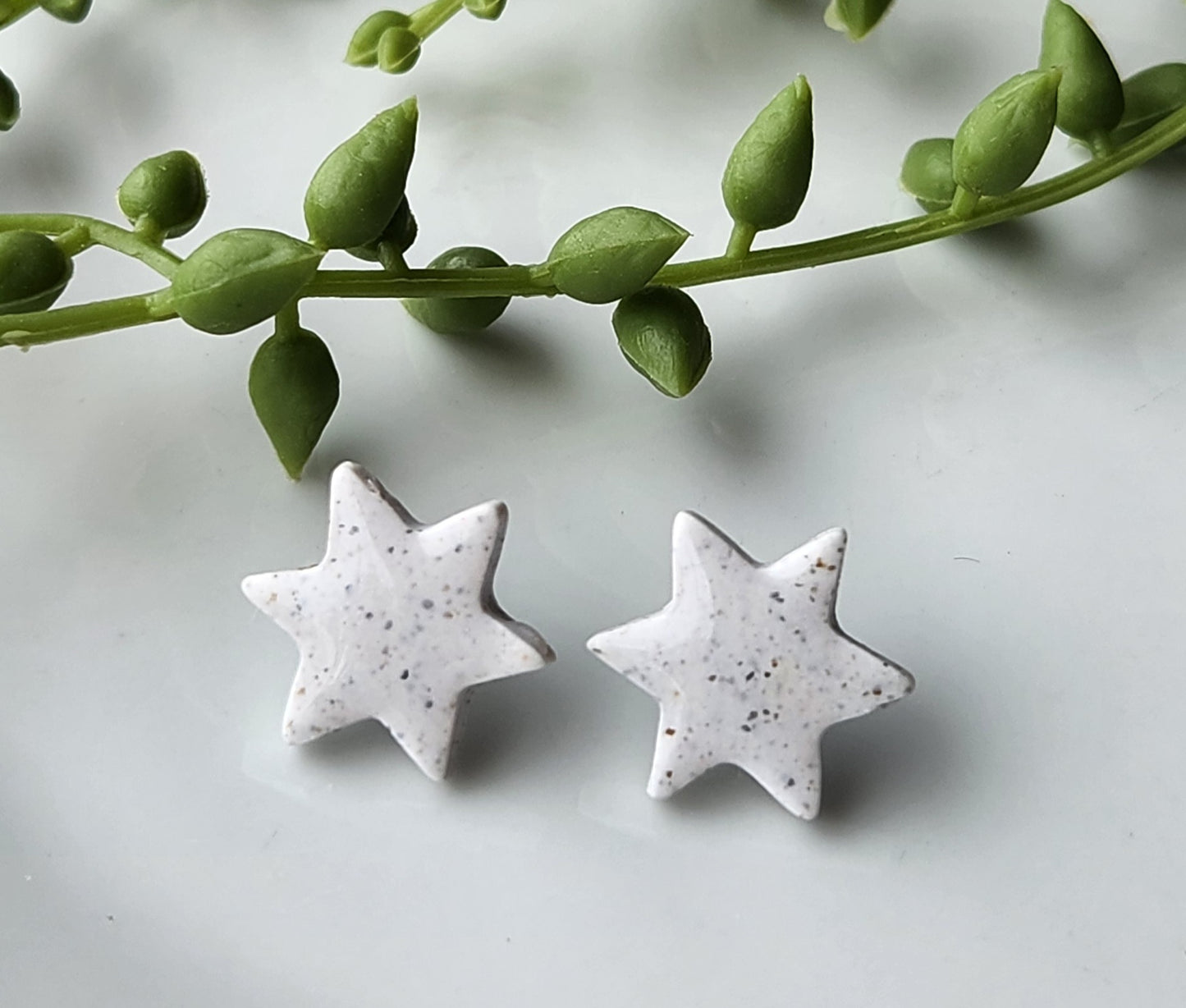 Handmade polymer clay earrings! Star shape stud with white background clay and black spekled dots. These stud earrings are perfect for any outfit and a staple accessory item for all. Studs are approximately .5" long and with resin for a glossy look.