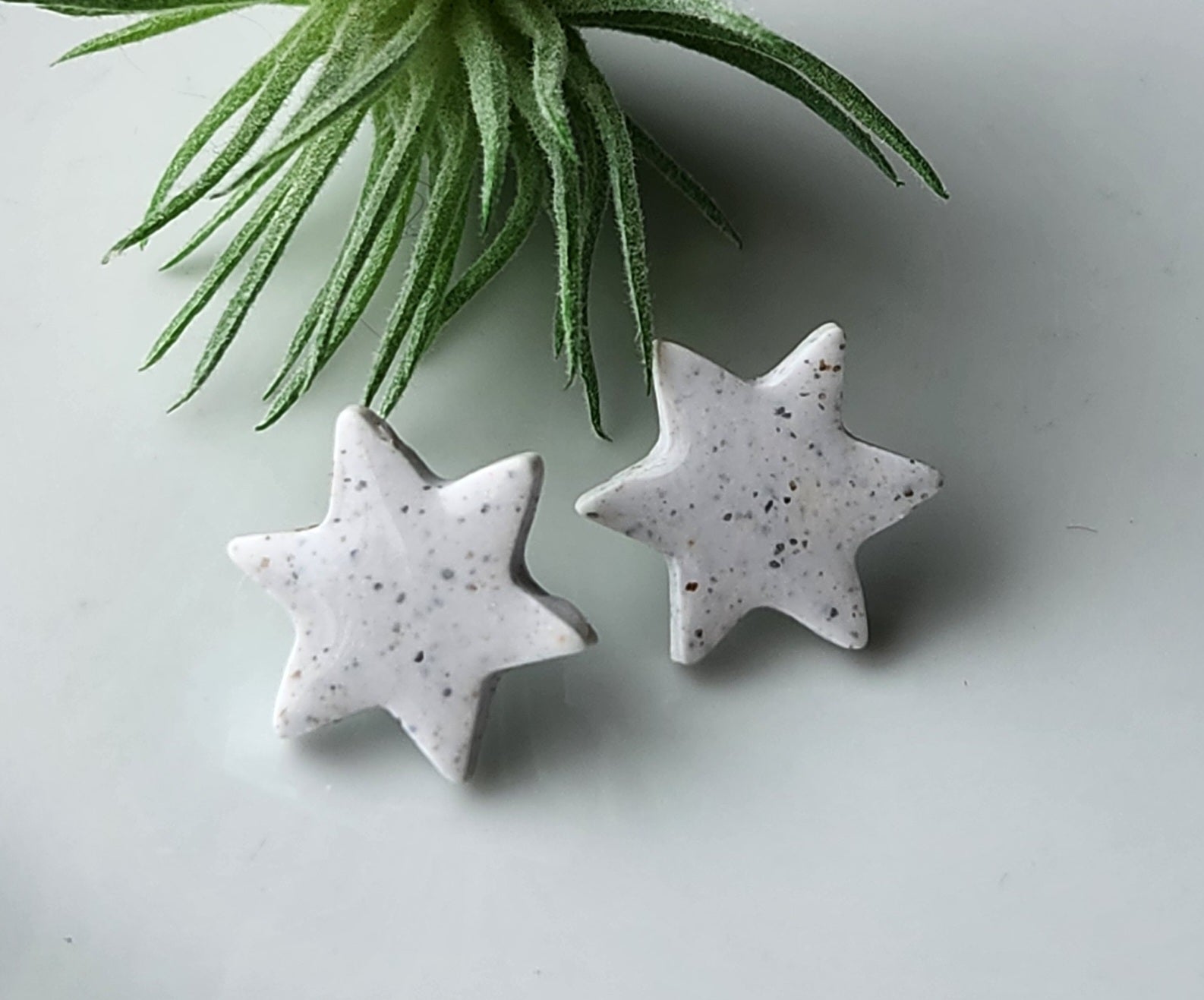 Handmade polymer clay earrings! Star shape stud with white background clay and black spekled dots. These stud earrings are perfect for any outfit and a staple accessory item for all. Studs are approximately .5" long and with resin for a glossy look.