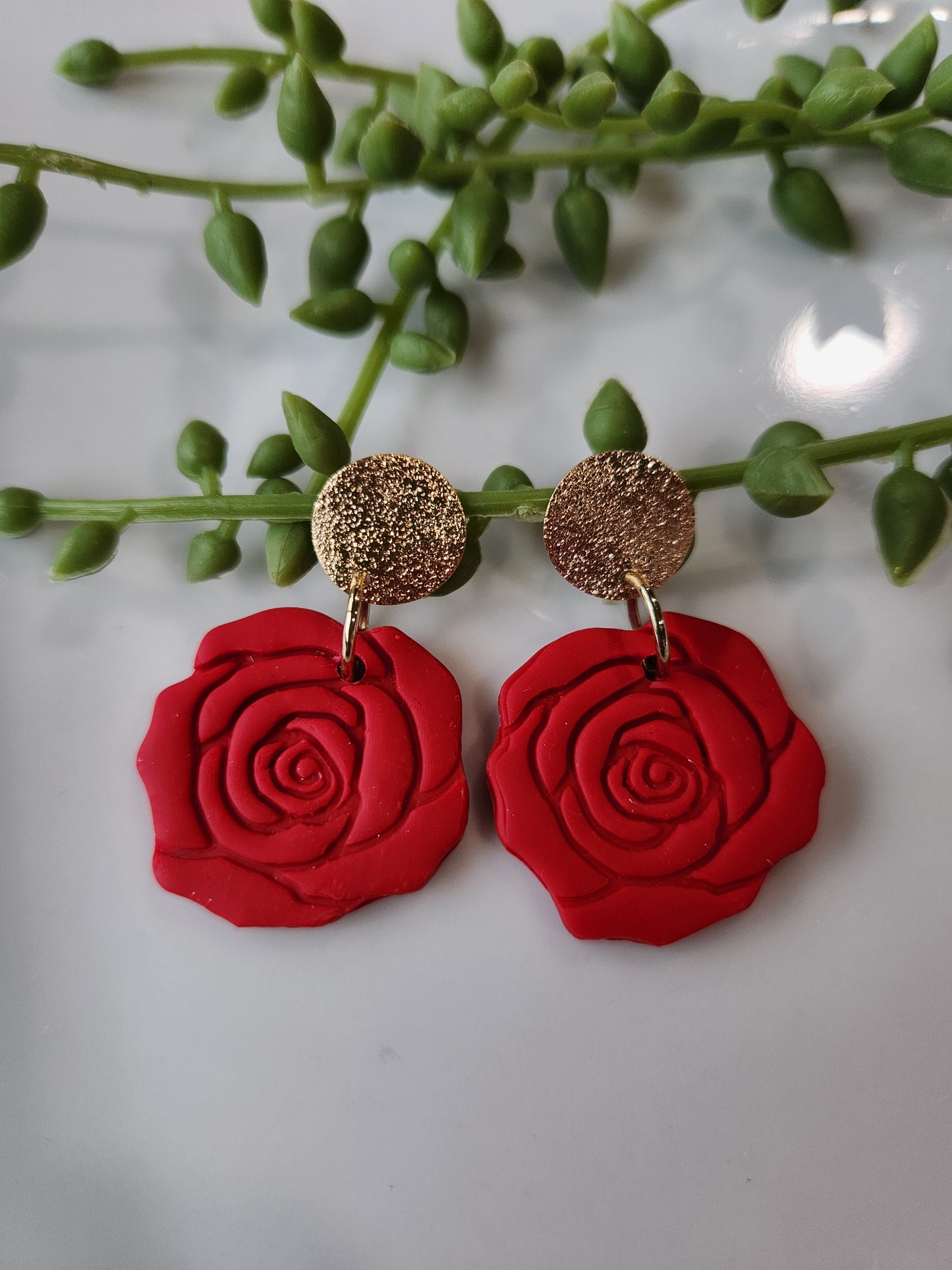 Handmade polymer clay earrings! These beautiful clay dangles are of a rose design with two different colors, red and red wine. They are matte with a shimmery gold-plated circle stud. Lightweight and approximately 1.5" long.