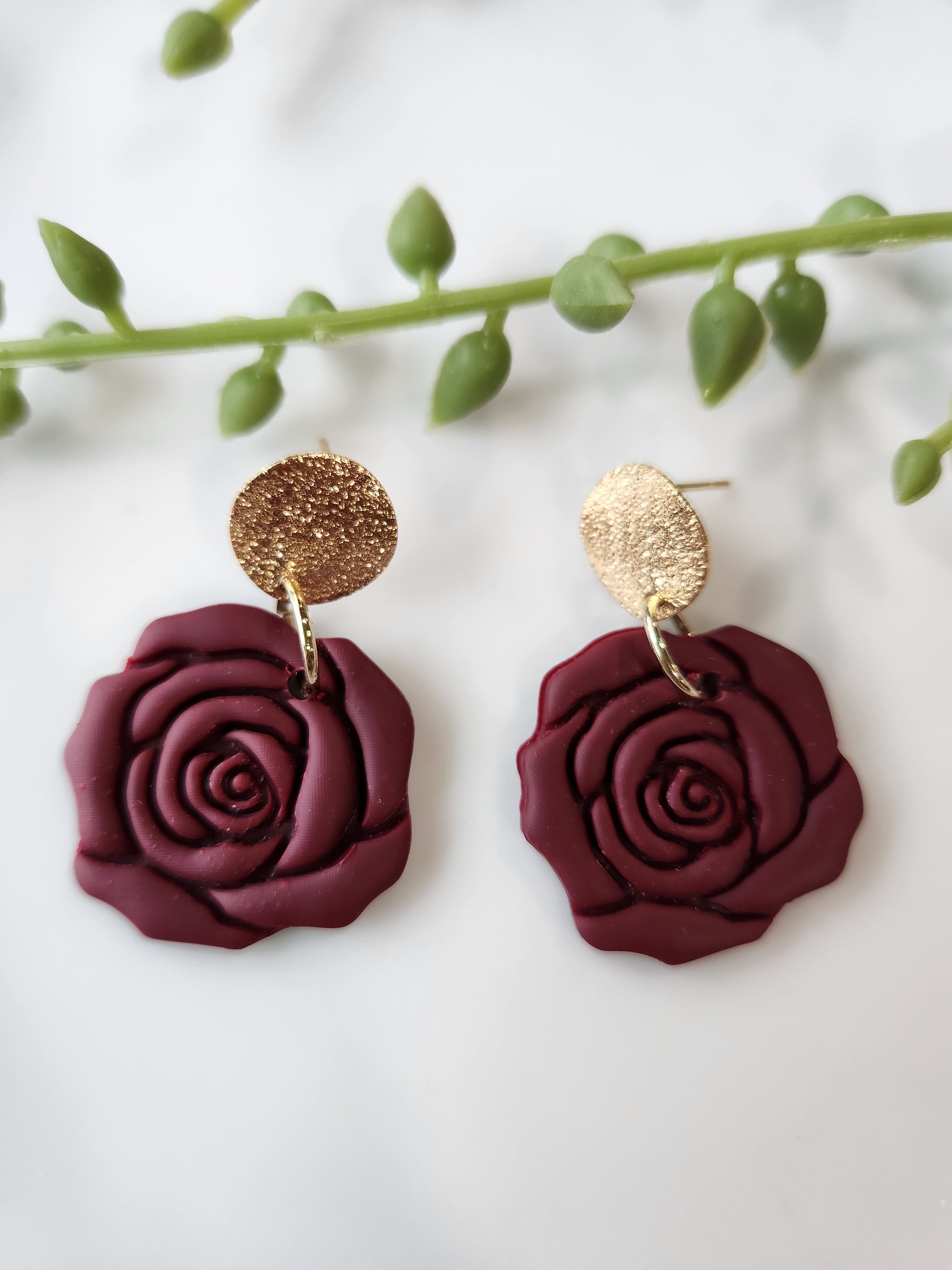 Handmade polymer clay earrings! These beautiful clay dangles are of a rose design with two different colors, red and red wine. They are matte with a shimmery gold-plated circle stud. Lightweight and approximately 1.5" long.