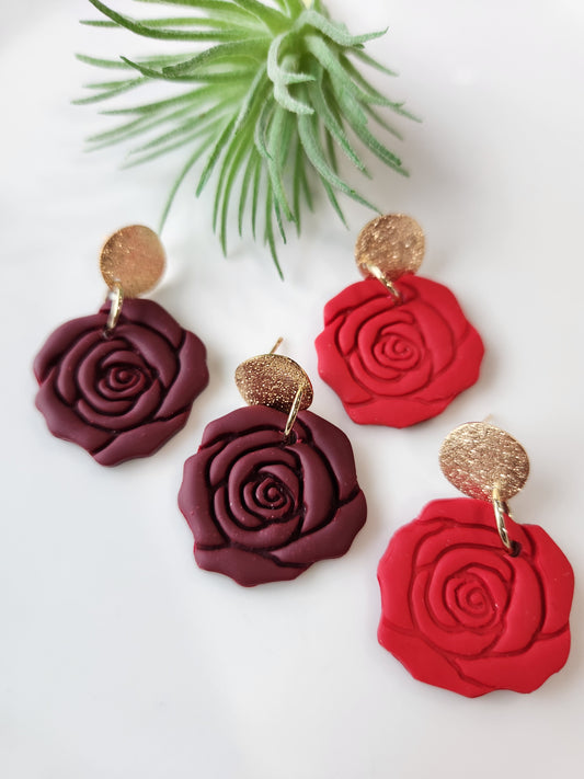 Handmade polymer clay earrings! These beautiful clay dangles are of a rose design with two different colors, red and red wine. They are matte with a shimmery gold-plated circle stud. Lightweight and approximately 1.5" long.