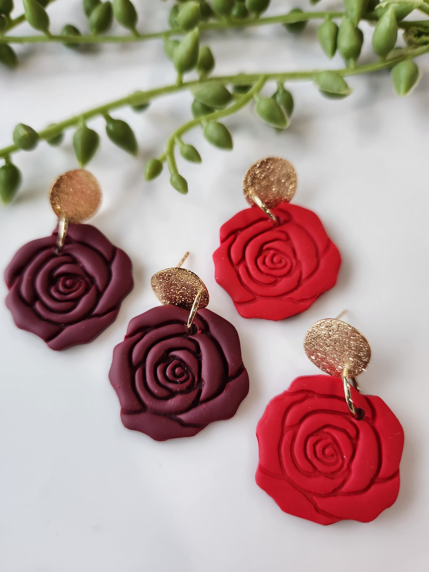 Handmade polymer clay earrings! These beautiful clay dangles are of a rose design with two different colors, red and red wine. They are matte with a shimmery gold-plated circle stud. Lightweight and approximately 1.5" long.