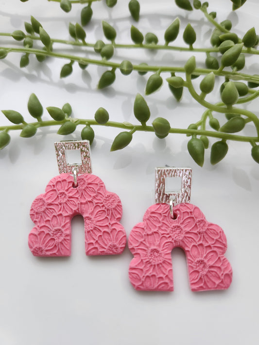 Handmade polymer clay earrings! These beautiful earrings are made of pink clay and with a scalloped-shaped design. They are textured with floral print throughout and with an open square silver plated stud. They are matte, lightweight, and approximately 2" long.