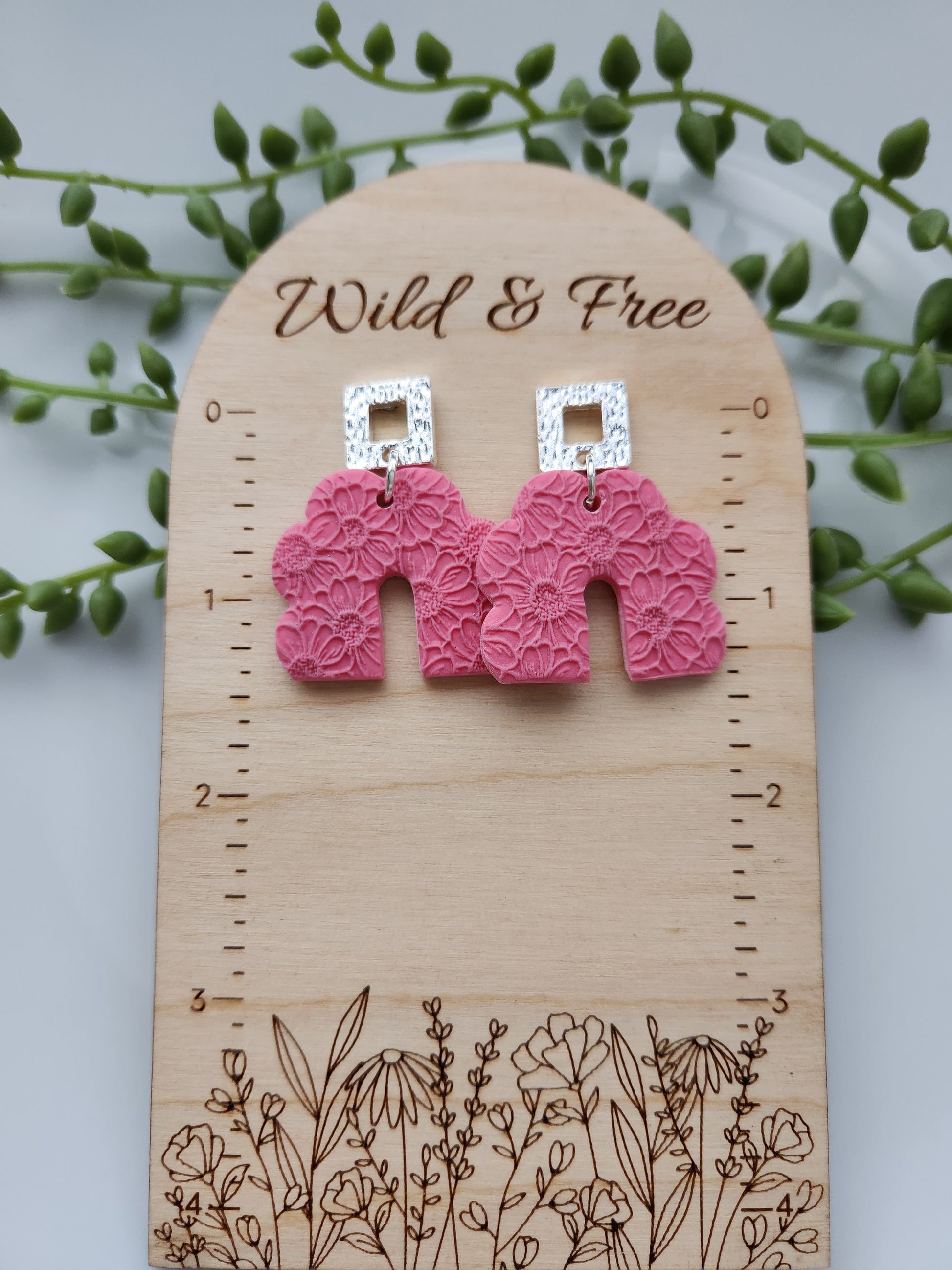 Handmade polymer clay earrings! These beautiful earrings are made of pink clay and with a scalloped-shaped design. They are textured with floral print throughout and with an open square silver plated stud. They are matte, lightweight, and approximately 2" long.