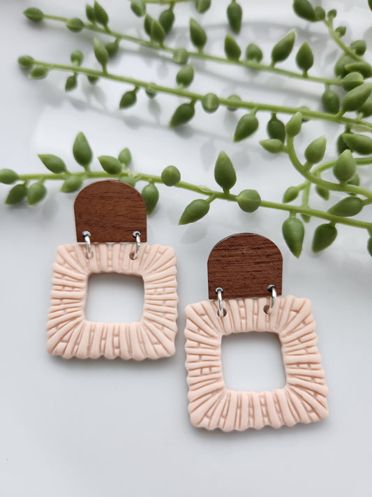 Handmade polymer clay blush earrings! These beautiful earrings are made out of polymer clay in a light blush color. They are square-shaped with an open square in the middle. The dome-shaped wood stud completes this dangle earring. These earrings are textured, lightweight, and approximately 2" long.