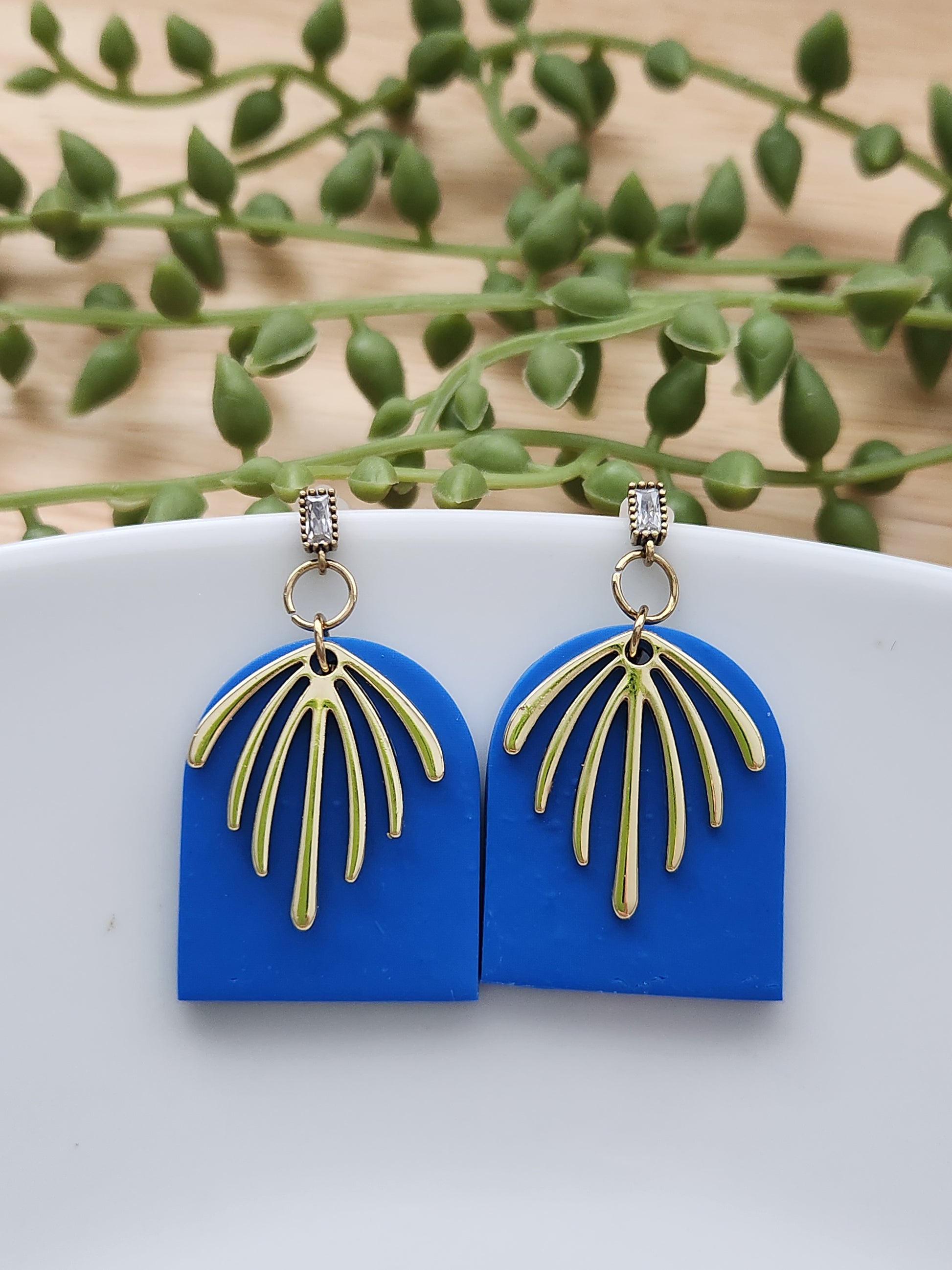 Handmade rich blue polymer clay earrings! This bright blue color is my favorite! These dangle earrings are of a dome shape with a gold-plated charm consisting of 7 lines facing down. A sterling silver needle zircon earring post completes this earring design. They are sure to stand out, lightweight, and approximately 2" long.