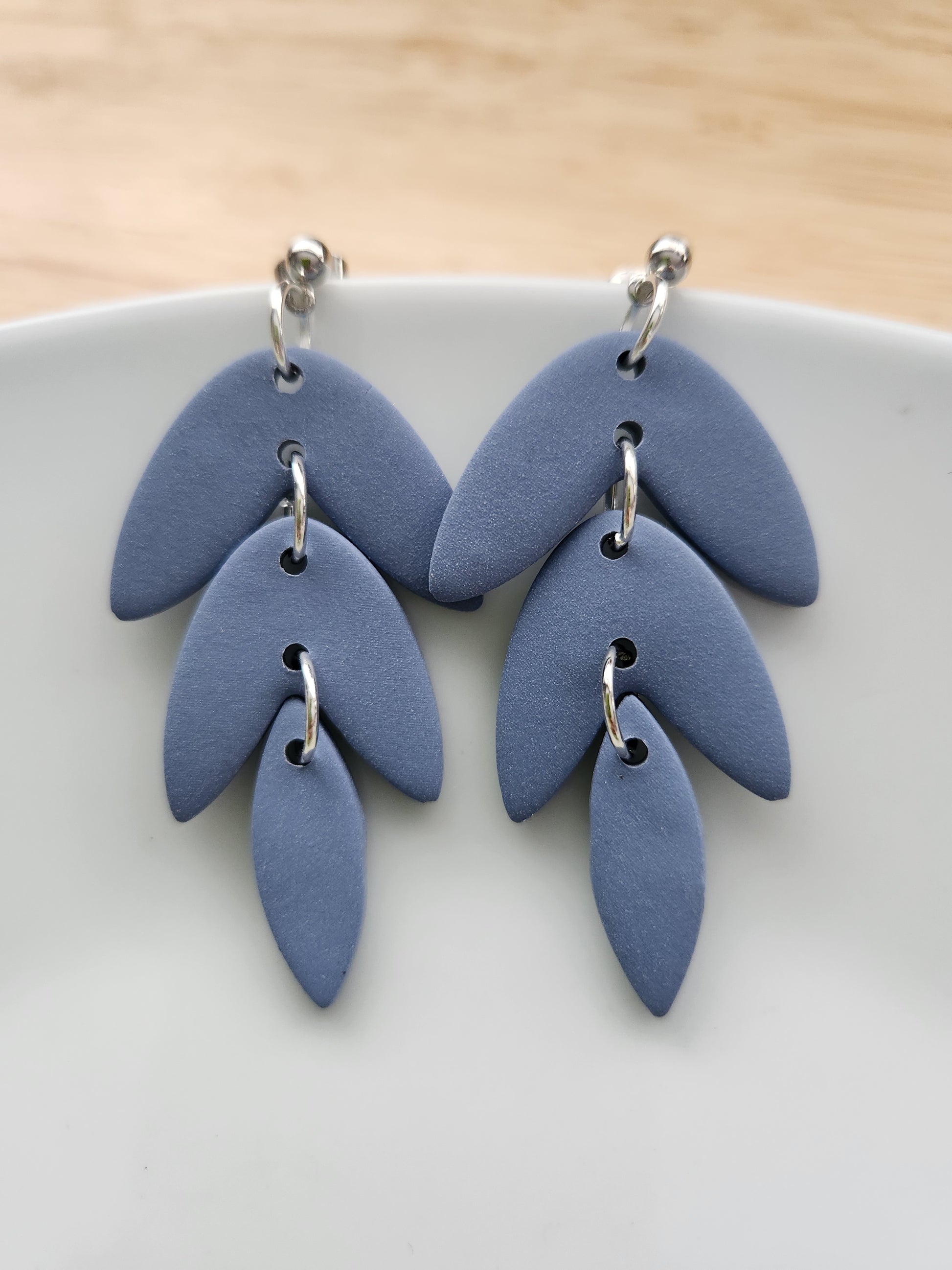 Handmade polymer clay earrings! This beautiful blue clay is perfect for any outfit and any occasion. Clay is cut out into leaf pieces cascading down. A silver-plated circle stud completes this look. These bold earrings are bold, matte, and approximately 2.5" long.&nbsp;