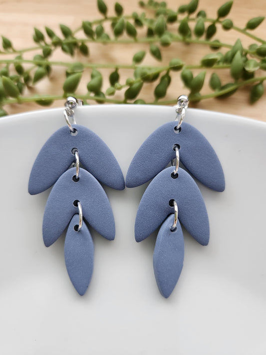Handmade polymer clay earrings! This beautiful blue clay is perfect for any outfit and any occasion. Clay is cut out into leaf pieces cascading down. A silver-plated circle stud completes this look. These bold earrings are bold, matte, and approximately 2.5" long.&nbsp;