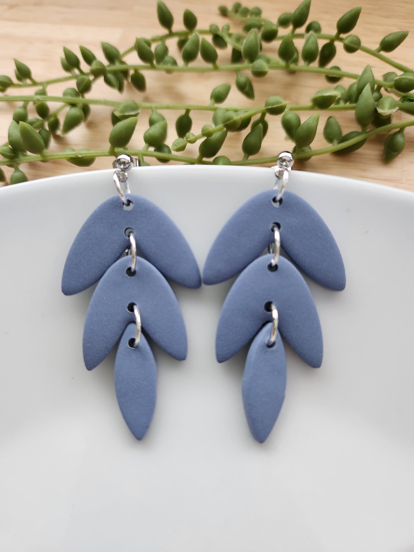 Handmade polymer clay earrings! This beautiful blue clay is perfect for any outfit and any occasion. Clay is cut out into leaf pieces cascading down. A silver-plated circle stud completes this look. These bold earrings are bold, matte, and approximately 2.5" long.&nbsp;