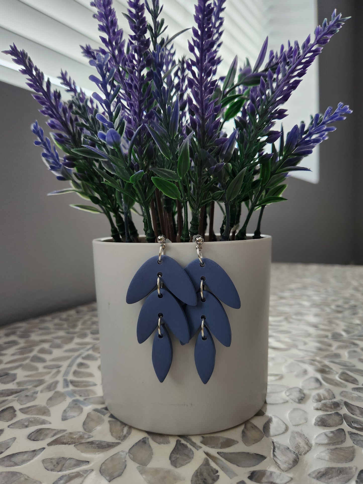 Handmade polymer clay earrings! This beautiful blue clay is perfect for any outfit and any occasion. Clay is cut out into leaf pieces cascading down. A silver-plated circle stud completes this look. These bold earrings are bold, matte, and approximately 2.5" long.&nbsp;