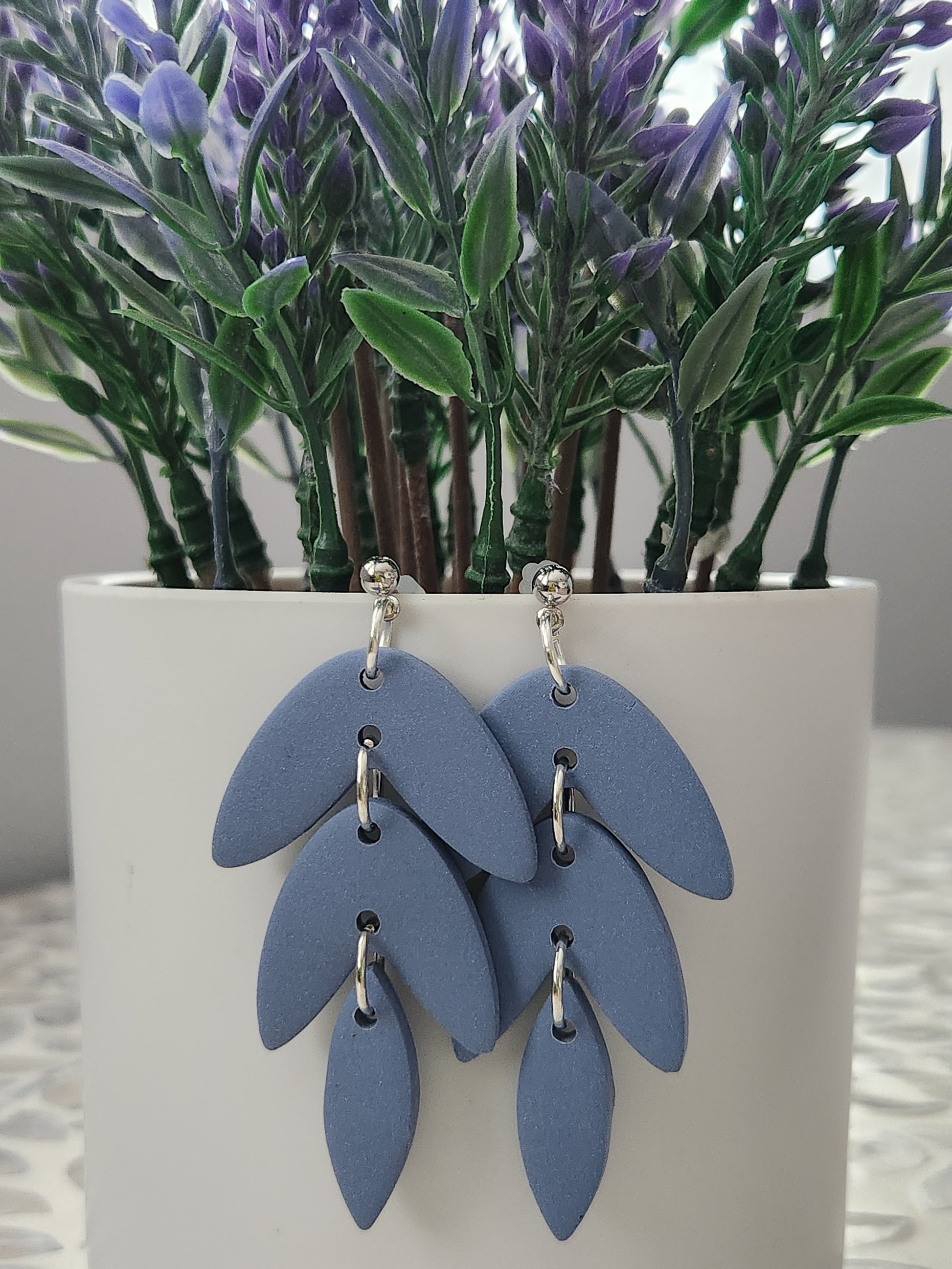 Handmade polymer clay earrings! This beautiful blue clay is perfect for any outfit and any occasion. Clay is cut out into leaf pieces cascading down. A silver-plated circle stud completes this look. These bold earrings are bold, matte, and approximately 2.5" long.&nbsp;