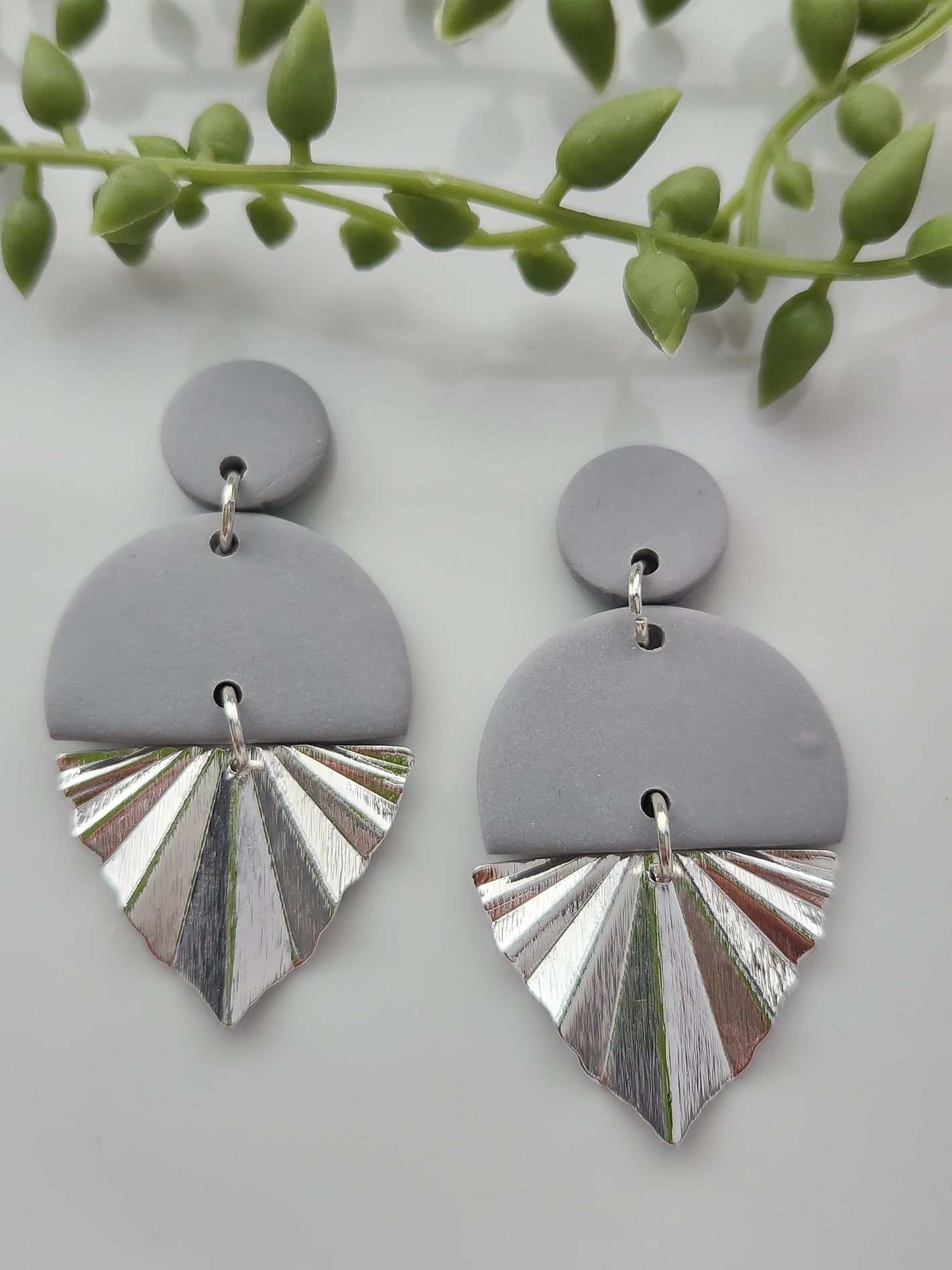 Handmade polymer clay earrings! Love this grey clay color! These earrings are designed with a circle stud, a cut-off large circle, and a shiny silver-plated triangle charm. They are sure to make any outfit stand out! Lightweight, matte, and approximately 2" long.
