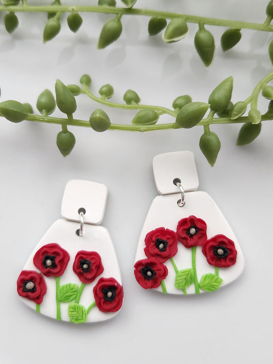 Handmade polymer clay earrings! These unique red poppy flower earrings are sure to stand out! White clay is the base of these earrings with four red poppy flowers. A white clay small square is used as a stud. Lightweight and approximately 1.5" long.