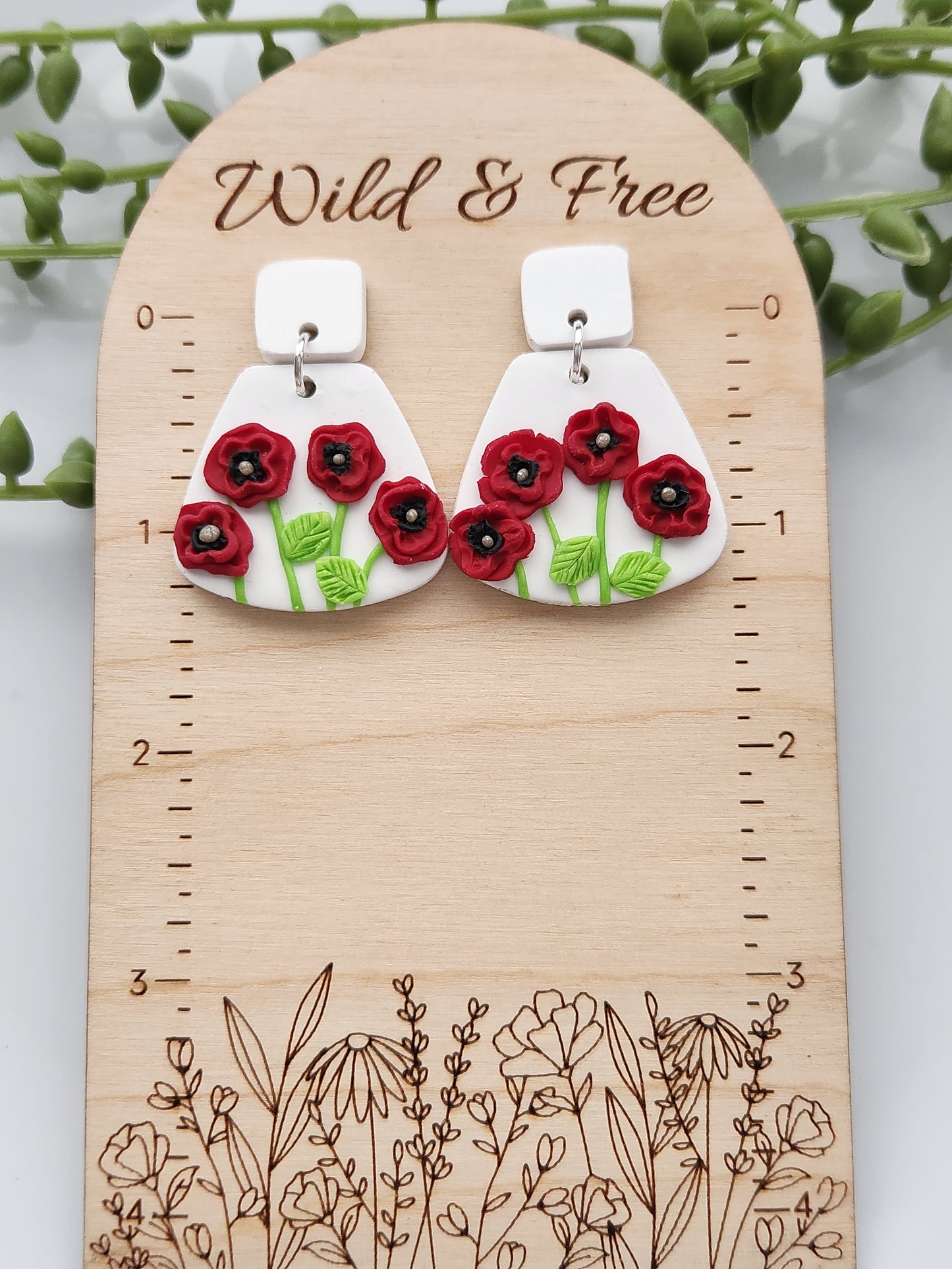 Handmade polymer clay earrings! These unique red poppy flower earrings are sure to stand out! White clay is the base of these earrings with four red poppy flowers. A white clay small square is used as a stud. Lightweight and approximately 1.5" long.