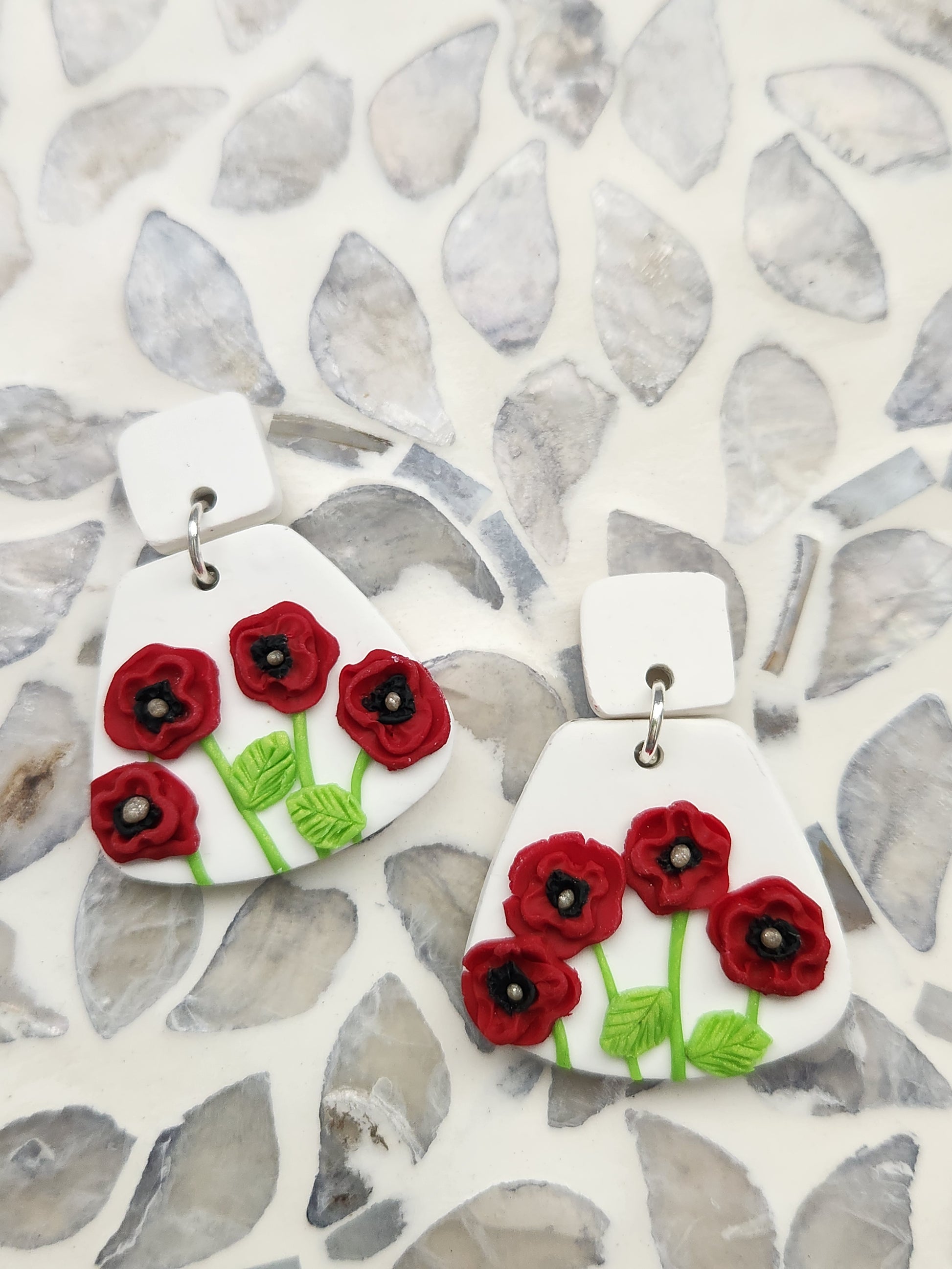 Handmade polymer clay earrings! These unique red poppy flower earrings are sure to stand out! White clay is the base of these earrings with four red poppy flowers. A white clay small square is used as a stud. Lightweight and approximately 1.5" long.