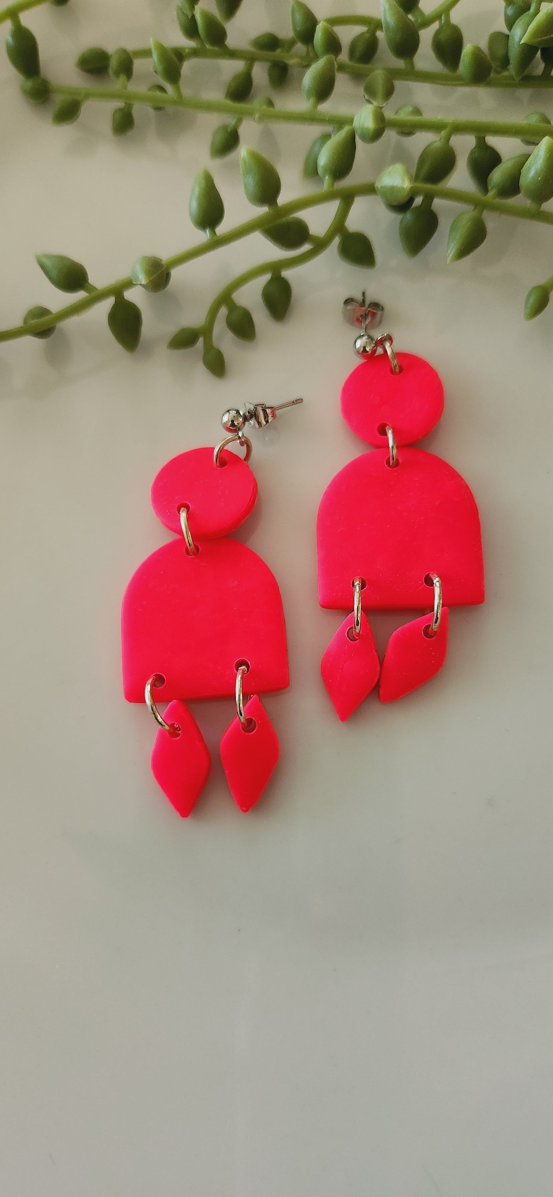 Handmade polymer clay earrings! These stunning hot pink clay earrings are sure to stand out. They consist of a clay circle with a half dome and two small diamond-shaped dangles. A circle ball stud completes this look. They are lightweight and approximately 2.5" long.