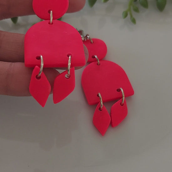 Handmade polymer clay earrings! These stunning hot pink clay earrings are sure to stand out. They consist of a clay circle with a half dome and two small diamond-shaped dangles. A circle ball stud completes this look. They are lightweight and approximately 2.5" long.